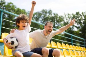 Padre e hijo disfrutan juntos un partido en el estadio, viviendo el regalo ideal para Papá lleno de pasión y momentos inolvidables.