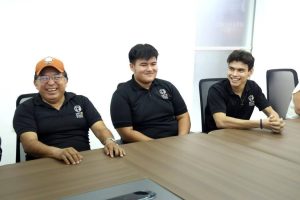 Abelardo, Emilio y Eulogio reciben la bandera nacional durante la ceremonia de abanderamiento en la UPY, preparándose para destacar en el Mundial de Robótica en Rumania.