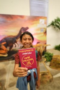 Niñas y niños reciben con entusiasmo su Pasaporte Aventura en el stand de Cultur durante la Feria Yucatán Xmatkuil 2025.