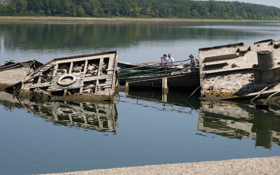 La Chispa informa que descubren naufragios de la Segunda Guerra Mundial gracias al nivel histórico más bajo del río Danubio. Las olas de calor y la sequía que afectan a Europa provocaron un descenso excepcional del caudal, alterando el transporte fluvial, amenazando infraestructuras críticas y dejando expuestos vestigios ocultos durante décadas e incluso milenios.
Buques nazis reaparecen después de 80 años
A lo largo de distintos tramos del segundo río más extenso de Europa comenzaron a aparecer embarcaciones de la Segunda Guerra Mundial, explosivos sin detonar y restos fósiles de un mamut lanudo. Según Smithsonian Magazine, la reducción del agua permitió acceder a sectores del lecho normalmente cubiertos.
El hallazgo también demuestra cómo los fenómenos climáticos extremos pueden transformar temporalmente el paisaje arqueológico y revelar patrimonio histórico que requiere vigilancia especializada.
Descubren naufragios de la Segunda Guerra Mundial
Cerca de Prahovo, Serbia, la bajante dejó visibles numerosos buques de guerra alemanes hundidos durante la retirada nazi de 1944. Los militares alemanes habrían hundido alrededor de 200 embarcaciones para evitar que fueran capturadas y bloquear la navegación del Danubio.
Más de ocho décadas después, los restos continúan dificultando el tránsito cuando baja el nivel del río. Según datos citados por Popular Science, Serbia pierde aproximadamente USD 5,75 millones anuales por las interrupciones relacionadas con estos naufragios.
Retirar barcos hundidos sigue siendo peligroso
En 2024, Serbia y el Banco Europeo de Inversiones impulsaron un proyecto para retirar 21 barcos. La operación exige máxima seguridad porque algunas embarcaciones todavía contienen munición. Al menos dos fueron enterradas nuevamente bajo el fondo.
El descenso extraordinario podría facilitar nuevas labores de recuperación, aunque cada intervención requiere especialistas, equipos adecuados y protocolos para evitar detonaciones.
Más hallazgos bajo las aguas
La sequía también expuso un barco posiblemente fechado en 1937 en Opatovac, Croacia. Aficionados a la pesca con imán recuperaron un amplificador de radio y casquillos de bala. En Budapest, una bomba de la Segunda Guerra Mundial obligó a cerrar temporalmente un puente.
Mamut lanudo aparece en Bulgaria
Los descubrimientos no se limitaron a la historia militar. En la ribera búlgara aparecieron restos de un mamut lanudo, entre ellos una mandíbula inferior, dos colmillos, un omóplato y una pieza posiblemente correspondiente a una costilla.
Estos descubrimientos convierten al Danubio en un inesperado archivo natural e histórico. Así, descubren naufragios de la Segunda Guerra Mundial mientras la misma bajante permite estudiar evidencias de diferentes épocas.
Un río estratégico en alerta
Con unos 2.850 kilómetros y diez países atravesados, el Danubio es esencial para mercancías, energía y economía regional. La sequía también afectó barcazas en Serbia, centrales nucleares de Hungría y Rumania, y provocó que un crucero quedara varado en Bulgaria.