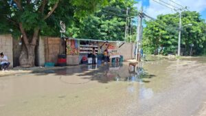 Padres de familia denuncian calles inundadas, baches ocultos y agua estancada frente a la primaria Tuumben K'iin y el preescolar Mejen Puksi'ik'al, en la colonia El Roble Agrícola, donde estudiantes y peatones enfrentan riesgos diariamente.